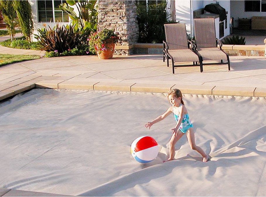 Image of a little girl playing on top of a pool cover